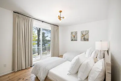a white bedroom with two beds and a window at Lakefront Retreat Hot Tub Outdoor Sauna Dock Swim Stunning Views! in Rosseau