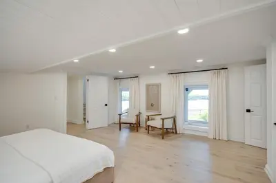 a white bedroom with a bed and a desk at Lakefront Retreat Hot Tub Outdoor Sauna Dock Swim Stunning Views! in Rosseau