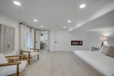 a white bedroom with a large white bed and chairs at Lakefront Retreat Hot Tub Outdoor Sauna Dock Swim Stunning Views! in Rosseau