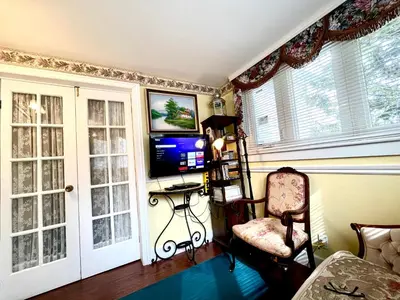 a living room with a chair and a television at Barker House 1# Suite-heart of oldtown in Niagara on the Lake