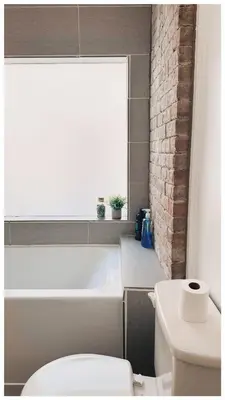 a bathroom with a tub and a toilet and a window at Cozy Place on Main Floor in Toronto