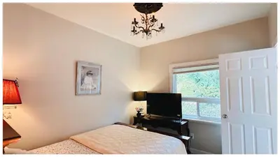 a bedroom with a bed and a desk with a television at Cozy Place on Main Floor in Toronto