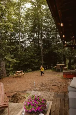 a person walking in a yard with flowers on a deck at Waterfront private cottage on Koshlong Lake in Haliburton