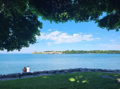 two people sitting on a stone wall near the water at Cozy Home in Niagara-on-the-Lake in Niagara on the Lake