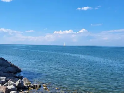 a boat in the ocean with a sailboat in the distance at Cozy Home in Niagara-on-the-Lake in Niagara on the Lake