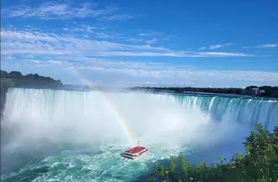 a boat in front of a waterfall with a rainbow at Cozy Home Close to Attractions in Niagara Falls in Thorold