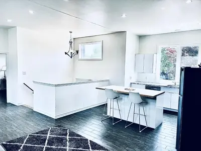 a white kitchen with a counter and stools at LaVida Exclusive Guest House(Rm#4) in London