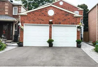 a brick house with two white garage doors at Toronto Spacious Cozy Mainfloor Room in Toronto