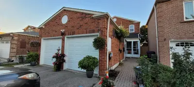 a brick house with two garage doors on it at Toronto Spacious Cozy Mainfloor Room in Toronto