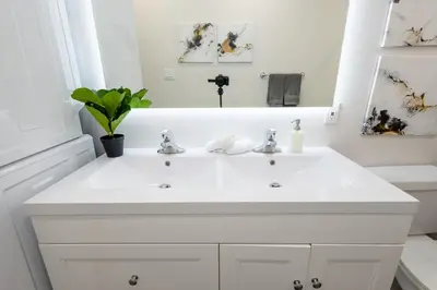 a white bathroom with a sink and a mirror at Victoria's Lookout in London