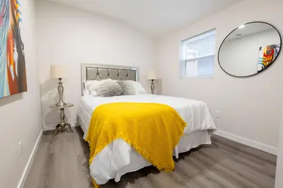 a white bedroom with a large bed with a yellow blanket at Victoria's Lookout in London