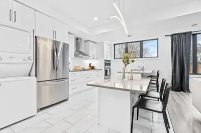 a white kitchen with white appliances and black chairs at Rent 8Bed 8Bath DowntownLondon Parking Wi-Fi in London