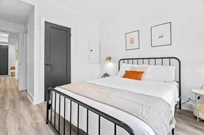 a white bedroom with a large bed with an orange pillow at Rent 8Bed 8Bath DowntownLondon Parking Wi-Fi in London