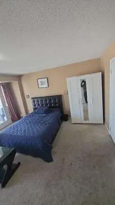 a bedroom with a blue bed and a cabinet at Cozy jets empire in Brampton