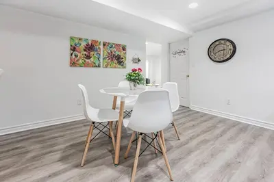 a dining room with a table and white chairs at Cozy Haven Retreat 2Bed Basement in Whitby