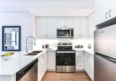 a kitchen with white cabinets and stainless steel appliances at Luxe Toronto Townhome, Rooftop Terrace, Parking in Toronto