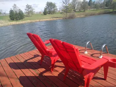 two red chairs sitting on a dock near the water at Waterfront Hideaway Private Suite-King bed room in Tottenham