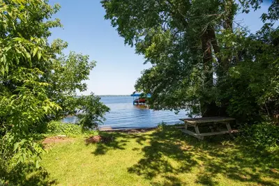 a picnic table sitting on the grass near the water at Dorado at The Kabins by The Falls in Fenelon Falls