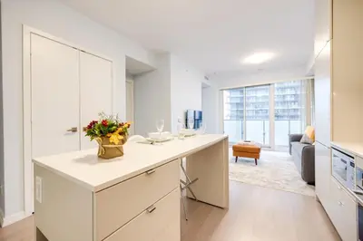 a white kitchen with a counter with flowers on it at Downtown Charm 2BR Retreat in Prime Location in Toronto
