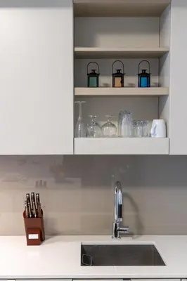 a kitchen counter with a sink and glasses on shelves at Downtown Charm 2BR Retreat in Prime Location in Toronto