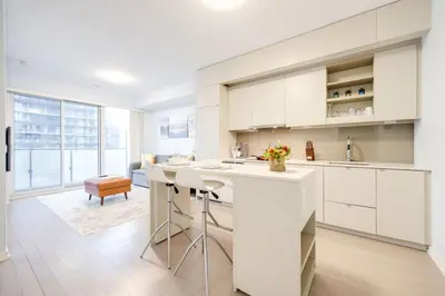 a kitchen with white cabinets and a kitchen island at Downtown Charm 2BR Retreat in Prime Location in Toronto