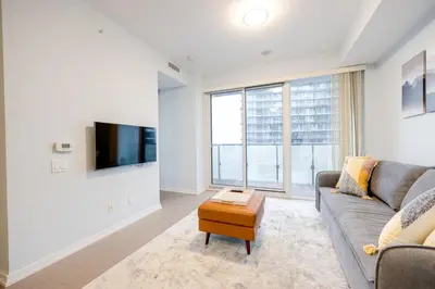 a living room with a couch and a tv at Downtown Charm 2BR Retreat in Prime Location in Toronto