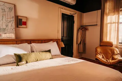 a bedroom with a bed and a chair and a window at Somewhere Inn Collingwood in Collingwood