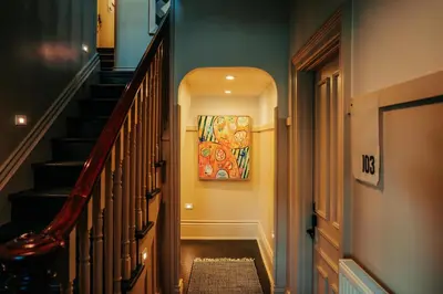 a hallway with a staircase with a painting on the wall at Somewhere Inn Collingwood in Collingwood