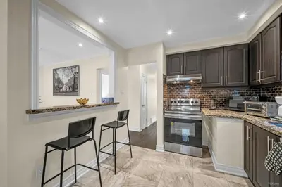 a kitchen with black cabinets and two bar stools at Luxury Renovated House in Prime Location with Parking in Toronto