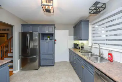 a kitchen with blue cabinets and a stainless steel refrigerator at Bright & Cozy 4BR Home for Your Family Stay With Optional Pool Access in Mississauga