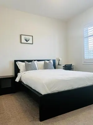 a bedroom with a large black bed with white sheets at Luxury Oakville Home, Hot Tub, Fireplace, New Home in Oakville