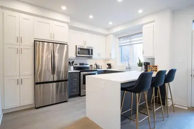 a kitchen with white cabinets and a stainless steel refrigerator at Modern 4-Bed Townhome with Cinema & Roof Terrace in Oakville
