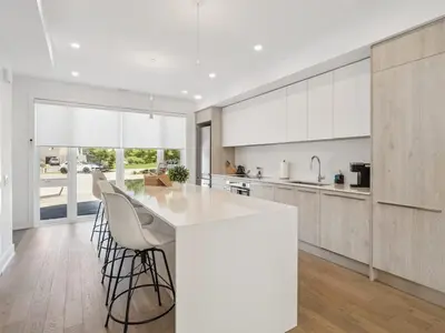 a kitchen with a white counter and chairs in it at Luxury Resort Villa in Muskoka in Gravenhurst