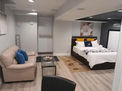 a bedroom with a bed and a couch and a chair at Furnished calm basement studio apartment in Mississauga