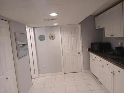 a kitchen with white cabinets and a white door at Furnished calm basement studio apartment in Mississauga