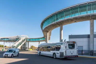 a white bus and a car parked in front of a building at Stylish 2BR: w/free parking & streaming! in Pickering