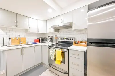 a kitchen with white cabinets and stainless steel appliances at Stylish 2BR: w/free parking & streaming! in Pickering