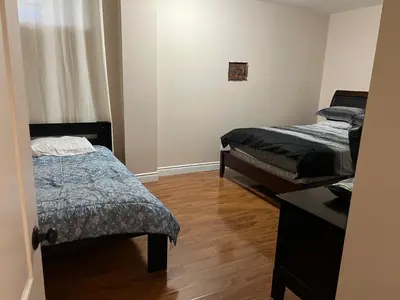 a room with two beds and a table in it at 2 bedroom basement with parking in Richmond Hill