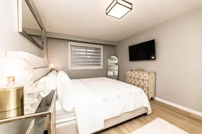 a bedroom with a white bed and a flat screen tv at Matilda’s Luxury House in Mississauga