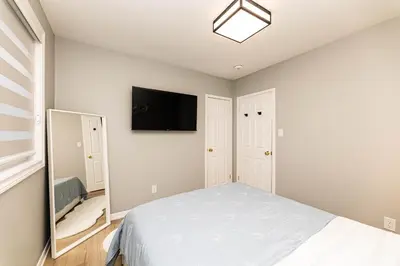 a bedroom with a bed and a flat screen tv at Matilda’s Luxury House in Mississauga