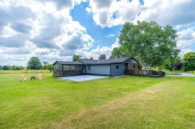 a small house in a field with a large yard at Serene 4BR house with Hot tub, Lake, Billiards and BBQ in Georgina