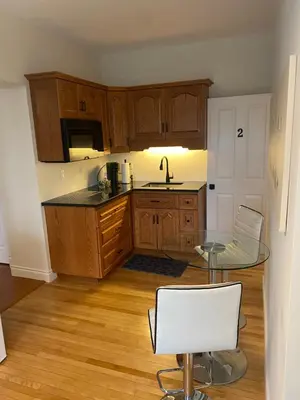 a kitchen with wooden cabinets and a glass table at North of Avon B&B Suites in Stratford