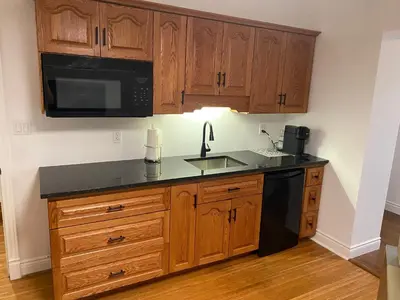 a kitchen with wooden cabinets and a sink and a microwave at North of Avon B&B Suites in Stratford