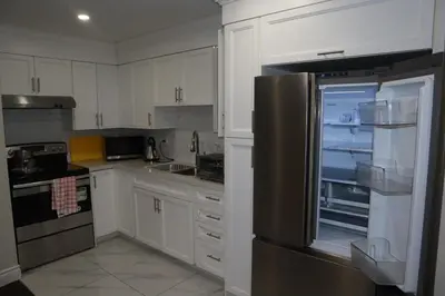 a kitchen with white cabinets and a stainless steel refrigerator at Stunning Furnished 2 Bedroom 2 Washroom Basement Apartment in Brampton