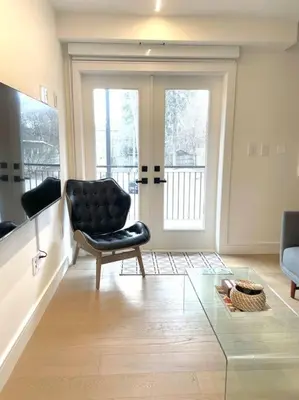 a living room with a chair and a glass table at Modern Apartment Close To The Beach with Parking in Toronto
