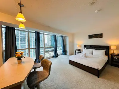a bedroom with a bed and a table and chairs at RivetStays - The Yonge in Toronto