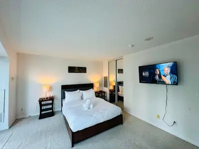 a bedroom with a bed with a tv on the wall at RivetStays - The Yonge in Toronto