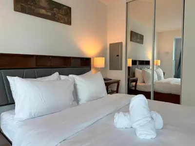 a bedroom with a bed with white sheets and a mirror at RivetStays - The Yonge in Toronto