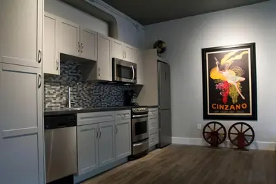 a kitchen with white cabinets and a painting on the wall at Woodbine Warehouse Apartment in Toronto