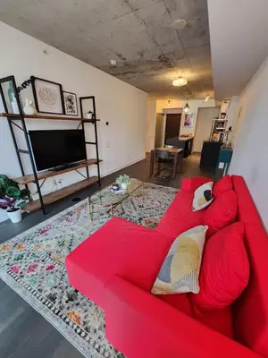 a red couch in a living room with a television at Chic 1BDR Loft with Office Space-Heart of Toronto in Toronto